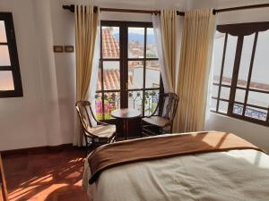 a bedroom with a bed and two chairs and a window at El Jardin De Su Merced B&B in Sucre
