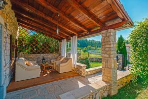 an outdoor patio with chairs and a stone wall at Albino in Kršan (Haus für 6 Personen) in Kršan