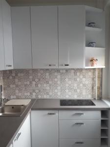 a kitchen with white cabinets and a sink at Aliz Apartman in Miskolc +3 photos
