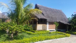 una casa con techo de paja y una palmera en Villa-Malaza, en Antalaha
