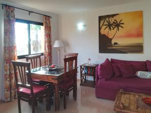 sala de estar con sofá púrpura y mesa en Apartment Gardenia, Oasis Tamarindo, en Corralejo