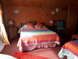 1 dormitorio con 1 cama con una manta colorida en Hostal y Cabañas Perla del Lago, en Puerto Guadal