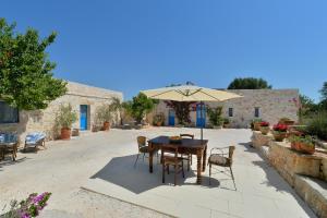 a table and chairs with an umbrella in a courtyard at Masseria Oreglia in Ceglie Messapica
