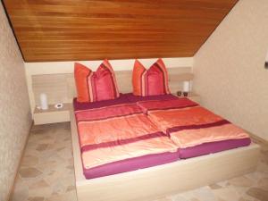 un letto con cuscini arancioni e viola in una stanza di Ferienwohnung Hartmann a Wehdel