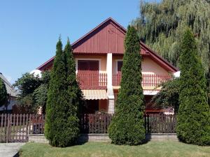 a house with trees in front of a fence at Üttörő út 177 B in Balatonfenyves