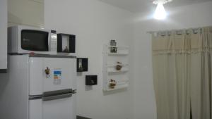 a kitchen with a refrigerator and a tv on a wall at Residencial Praia dos Corais in Coroa Vermelha