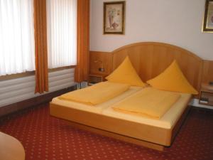 Un dormitorio con una cama con almohadas amarillas. en Hotel Gästehaus Theresia Garni en Mühlheim an der Donau