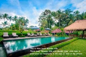 basen w ośrodku z leżakami i parasolami w obiekcie Alam Dania Cottage w mieście Ubud
