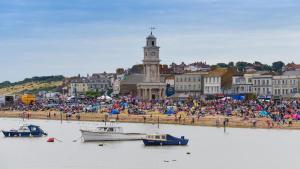 a crowd of people on a beach with boats in the water at Haven Retreat at Hillrise in Herne Bay