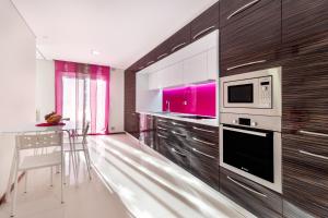 a kitchen with a table and a microwave at Pink Apartment - Spacious Apartment with Pool in Viana do Castelo