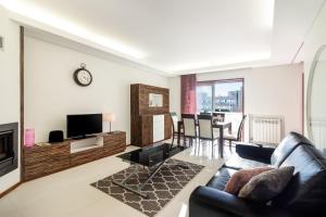 a living room with a couch and a tv at Pink Apartment - Spacious Apartment with Pool in Viana do Castelo