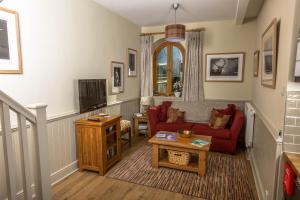 a living room with a red couch and a tv at The Dovecote, Stoke Farthing Courtyard in Broad Chalke