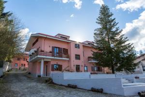 um edifício rosa com uma árvore em frente em Il Moscardino Country Resort em Serra San Bruno