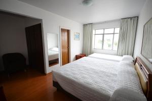a bedroom with a white bed and a window at Caravelle Palace Hotel in Curitiba