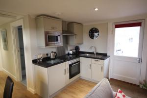 a kitchen with white cabinets and a sink and a microwave at Easter Arr Courtyard Apartment in Nairn