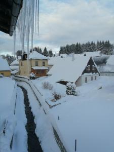 a snow covered village with houses and a stream at Penzion Tina in Pernink