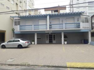 a white car parked in a parking lot in front of a building at Capão 2 Dormitorios in Capão da Canoa