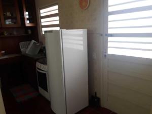 a white refrigerator in a kitchen with a window at Capão 2 Dormitorios in Capão da Canoa +2 photos