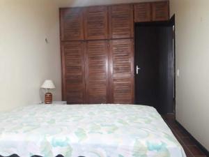 a bedroom with a large bed and a wooden closet at Capão 2 Dormitorios in Capão da Canoa