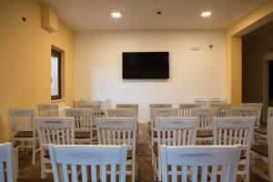 a room filled with white chairs and a flat screen tv at Il Moscardino Country Resort in Serra San Bruno