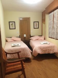 a bedroom with two beds with pink sheets and a chair at Casa Sanabresa in Galende