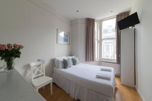 ロンドンにある23のベッドルーム1室(ベッド1台、椅子、窓付)