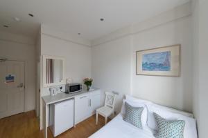 a bedroom with a bed and a desk with a microwave at Matheson Olympia Hotel in London