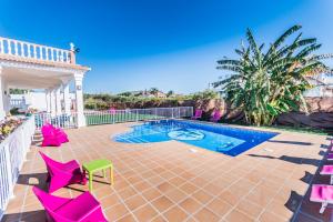 un patio avec des chaises roses et une piscine dans l'établissement Cubo's Villa San Jose, à Alhaurín el Grande
