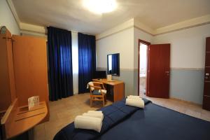 a bedroom with a blue bed and a desk with a computer at Santa Lucia Hotel in Corigliano Calabro