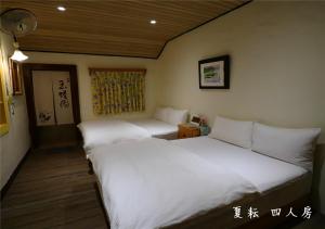 
a bed room with a white bedspread and white pillows at 玉蟾園民宿 寵物友善 YuChanYuan B&B in Chishang

