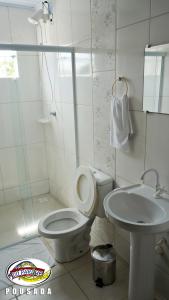 a white bathroom with a toilet and a sink at Do Parque Pousada in Penha