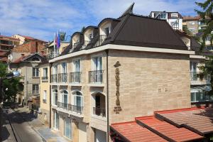 a building with a black roof on a city street at Agusta Hotel, Garden & SPA in Veliko Tŭrnovo