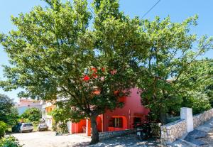 a tree in front of a red building at Apartments Josip in Pinezici