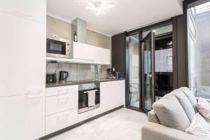 a kitchen with white cabinets and a couch in a room at Apartments with free parking in Oulu