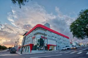 a building with a red roof on a city street at Hotel Sauípe in Cascavel