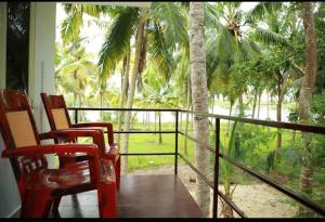 a porch with two chairs and a balcony with palm trees at Blue Birds Homestay in Cherai Beach