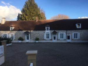 uma grande casa de tijolos com portas e janelas brancas em la ferme des ruelles em Moigny