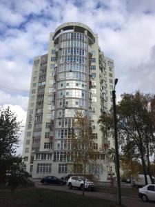 a tall building with cars parked in front of it at Apartment Alla in Chernihiv