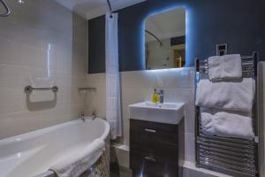 a bathroom with a tub and a sink and a mirror at The Castle Hotel, Conwy, North Wales - The Coaching Inn Group in Conwy