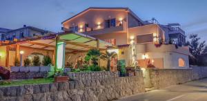 a large white house with a stone wall at Boutique Villa Revelin in Pag