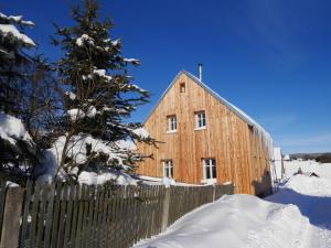 eine hölzerne Scheune im Schnee mit einem Zaun in der Unterkunft Olivia House in Abertamy