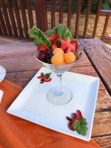 a bowl of fruit on a white plate on a table at Palm Spring Inn in Oranjestad