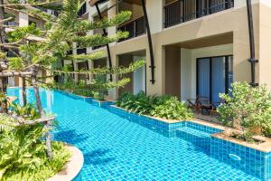 a swimming pool in front of a building with plants at Aurico Kata Resort & Spa - SHA Extra Plus in Kata Beach