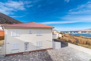 ein weißes Haus mit Blick auf das Wasser in der Unterkunft Apartmani Matej B in Pag