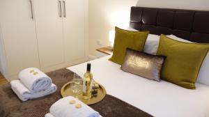 a bedroom with a bed with a bottle of wine and towels at Luxe Airport - Free Parking in Stanwell