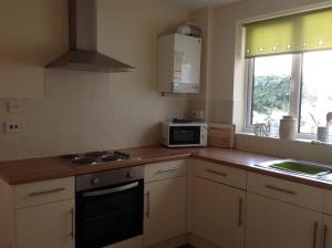 a kitchen with a stove and a microwave at Cricket View cottage in Redcar