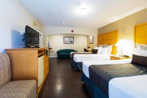a hotel room with two beds and a flat screen tv at Travelodge by Wyndham Merced Yosemite in Merced