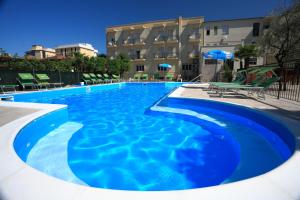 a large blue swimming pool in front of a building at Hotel Vannini in Rimini