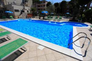 uma grande piscina azul com cadeiras e guarda-sóis em Hotel Vannini em Rimini