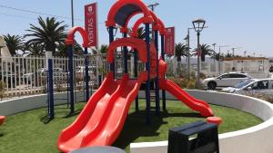 une aire de jeux avec toboggan rouge dans un parc dans l'établissement Departamento avenida del mar, à La Serena